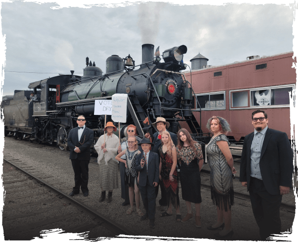 photo of people dressed in 20s clothing standing in front of the Roaring 20s themed train